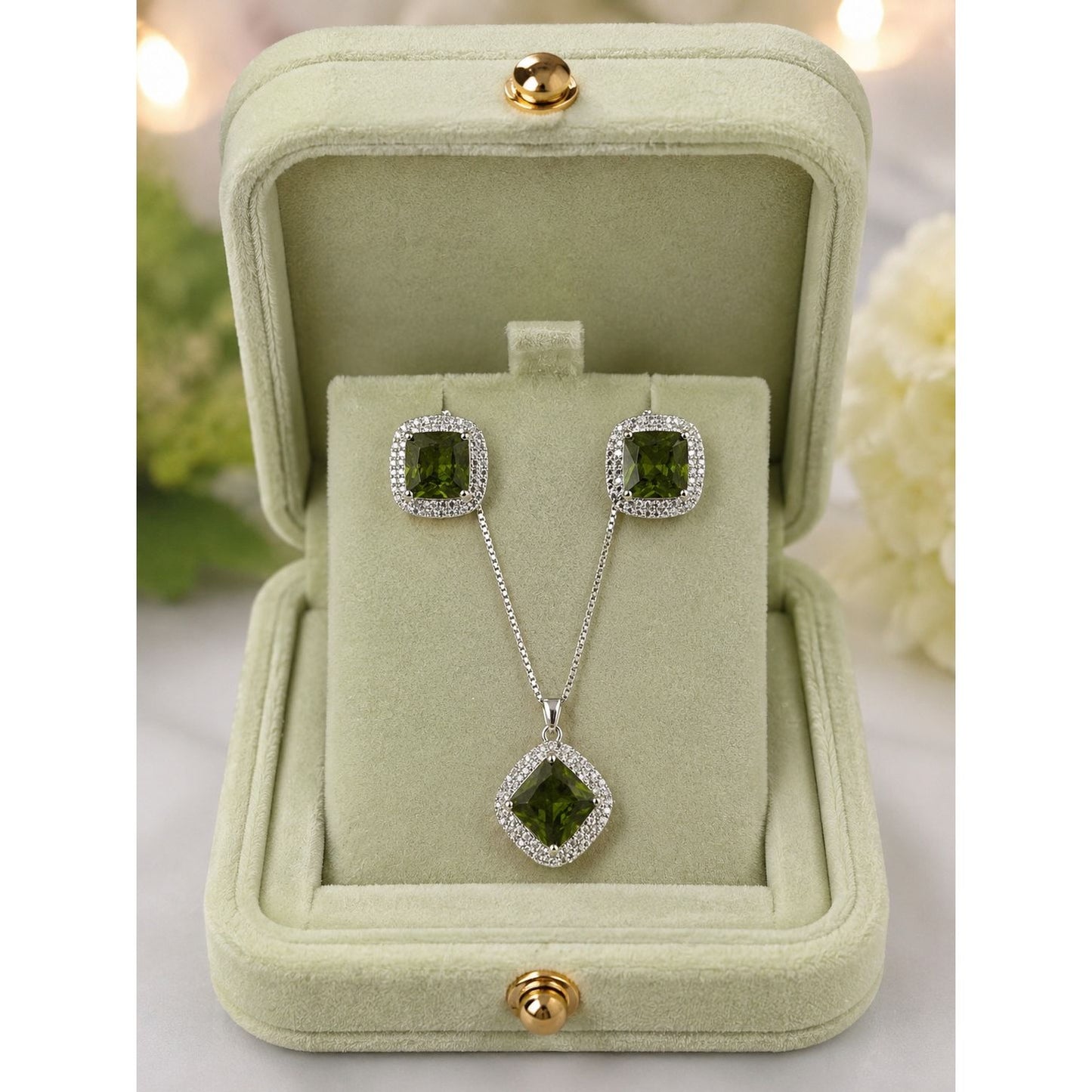 Emerald-green crystal halo pendant necklace and matching stud earrings displayed in a premium sage velvet jewelry gift box