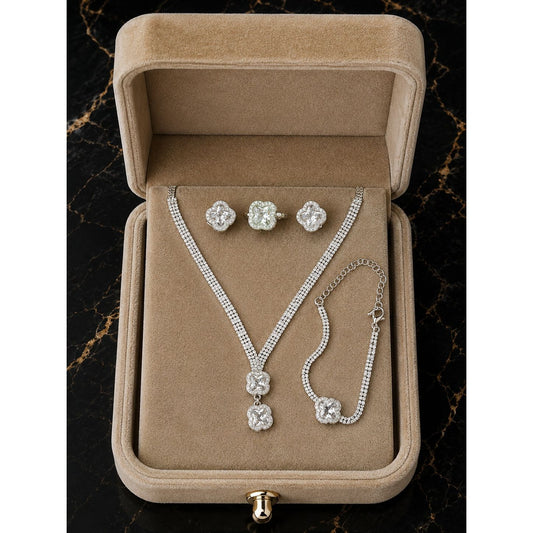 Luxury silver clover crystal jewelry set displayed in a premium champagne beige velvet jewelry box featuring a necklace, stud earrings, ring, and matching bracelet.