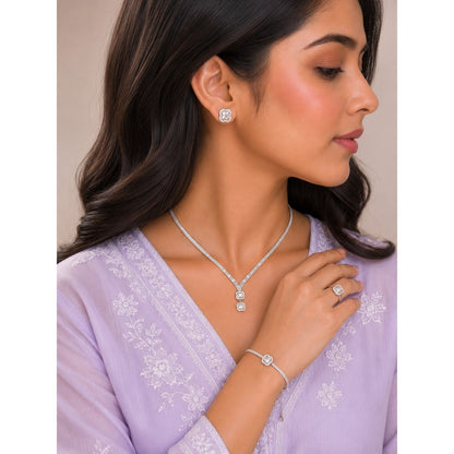 Model wearing a silver clover crystal jewelry set featuring matching stud earrings, double-drop pendant necklace, statement ring, and bracelet with sparkling faceted stones.