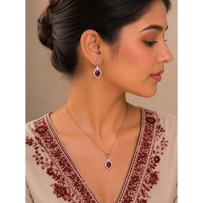 Model wearing a ruby red heartdrop pendant necklace and matching drop earrings with crystal accents and a silver-tone finish.