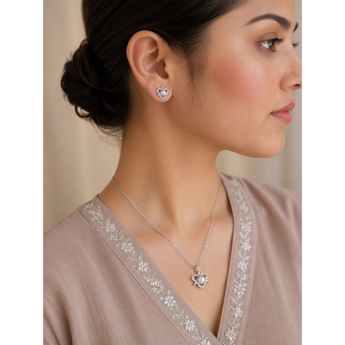 Model wearing a silver pearl blossom pendant necklace and matching floral stud earrings featuring pearl center stones and crystal accents.