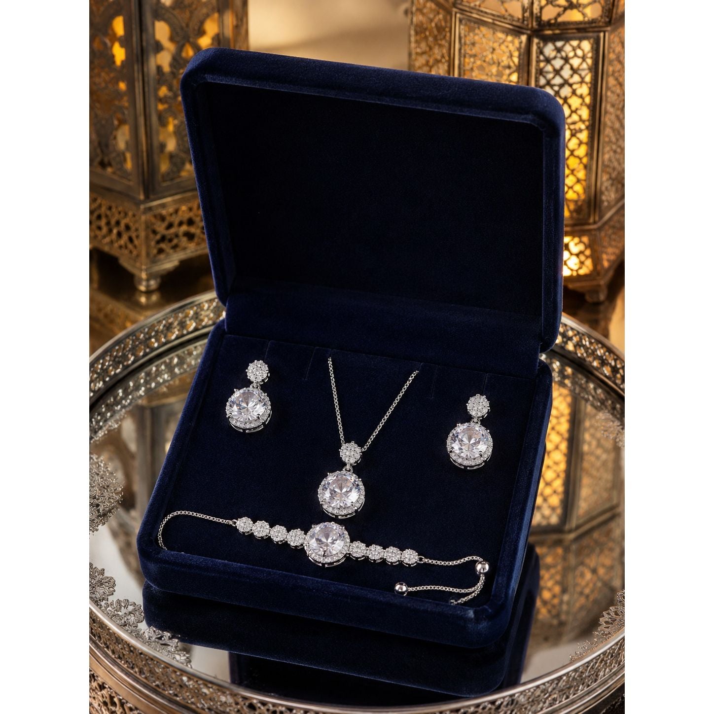 Luxury crystal jewelry set with matching necklace, earrings, and adjustable bracelet displayed in a premium navy velvet jewelry box with decorative lantern background.