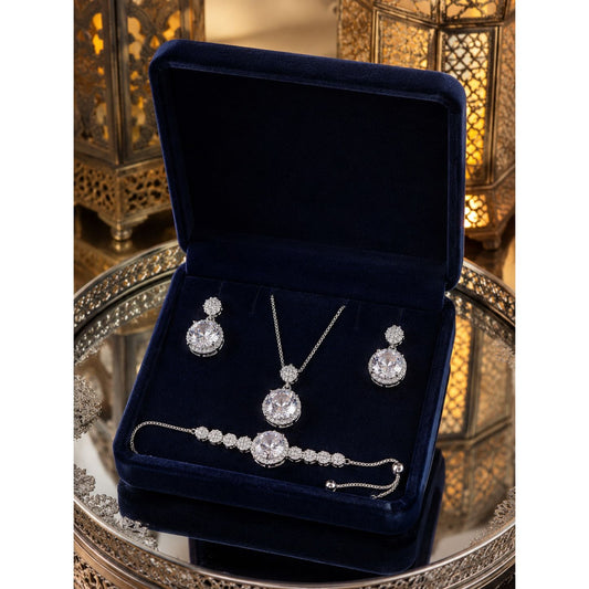 Luxury crystal jewelry set with matching necklace, earrings, and adjustable bracelet displayed in a premium navy velvet jewelry box with decorative lantern background.