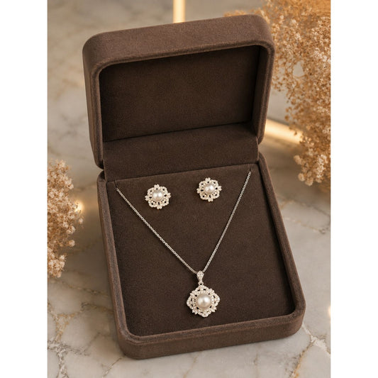 Pearl and crystal floral necklace and stud earrings set displayed in a premium brown velvet jewelry box on a marble surface.