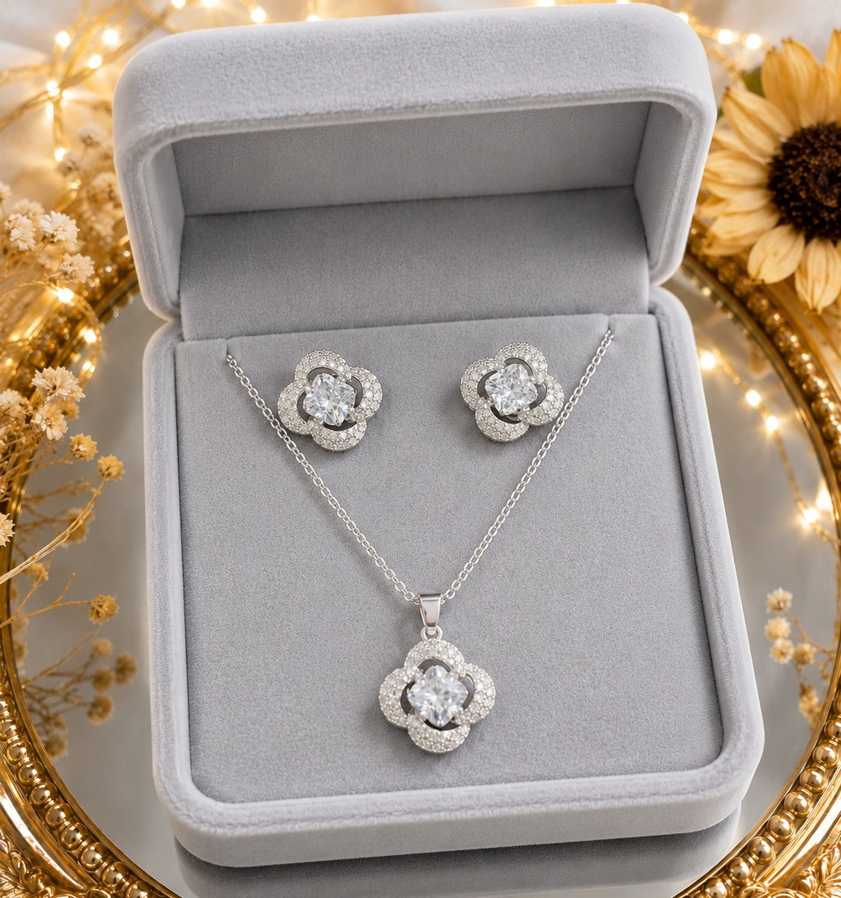 Crystal clover necklace and matching stud earrings displayed in a premium light grey velvet jewelry box with decorative floral accen