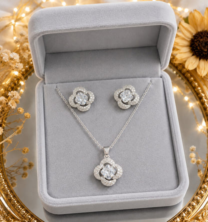 Crystal clover necklace and matching stud earrings displayed in a premium light grey velvet jewelry box with decorative floral accen
