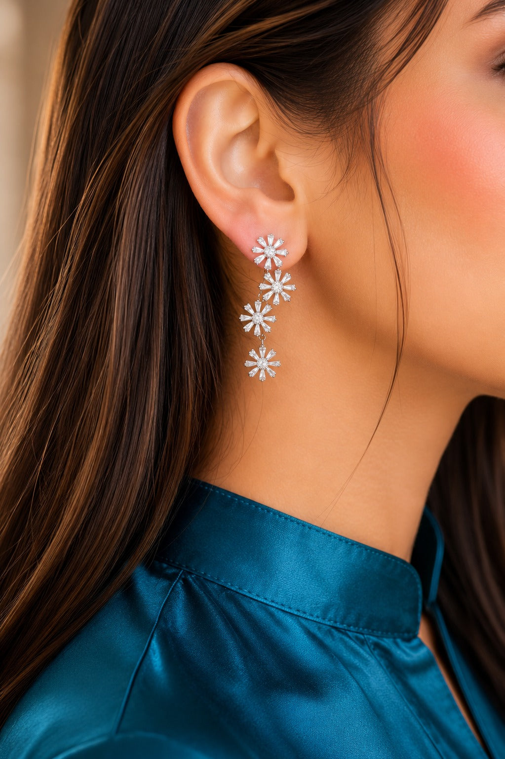 Silver floral cubic zirconia drop earrings worn by model with teal satin shirt, featuring four cascading flower motifs.