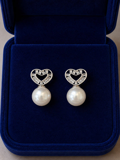 Silver heart pearl stud earrings with cubic zirconia displayed inside a premium navy velvet jewellery box.
