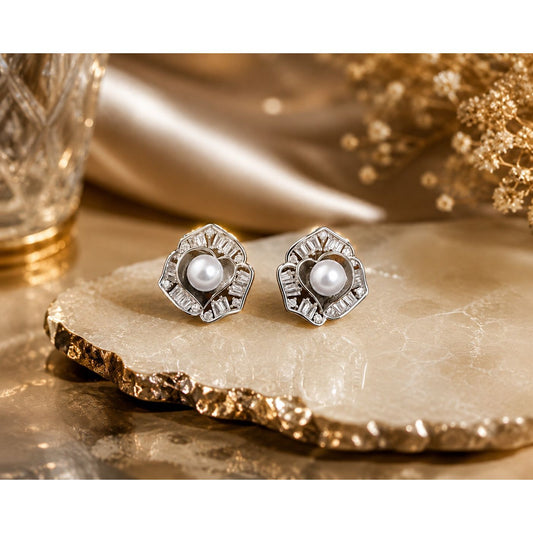 Silver-tone pearl and crystal floral stud earrings displayed on a premium natural stone slab with a luxury decorative background and warm ambient lighting.