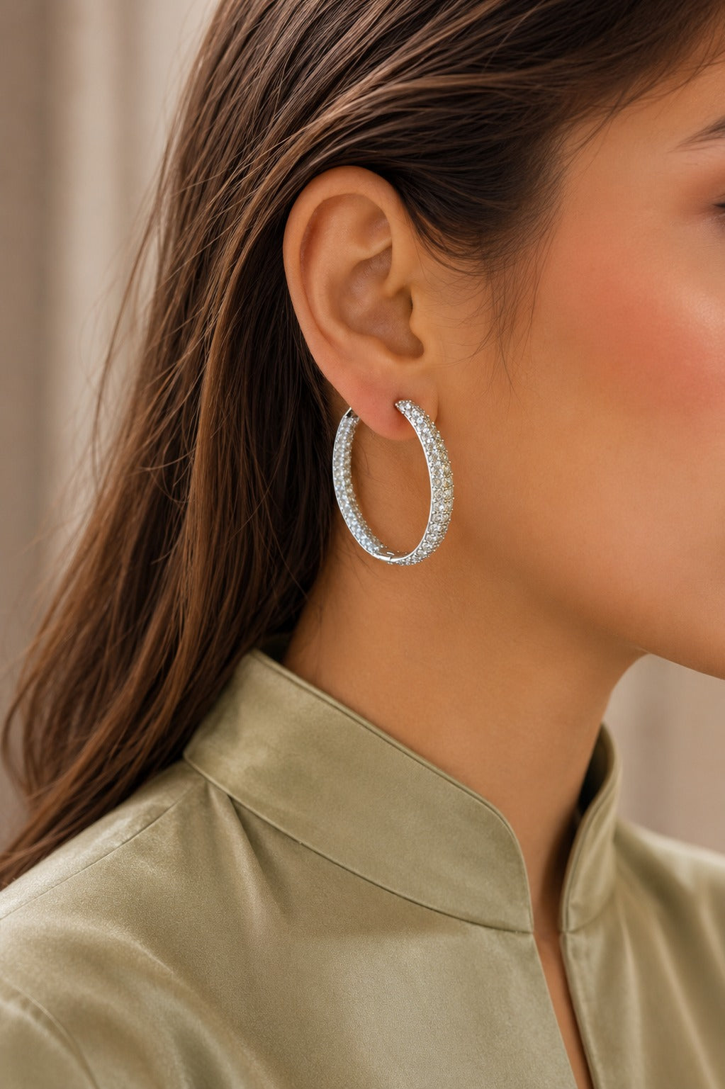 Model wearing silver crystal hoop earrings with a sage green satin collar blouse, showcasing timeless luxury hoop earrings.