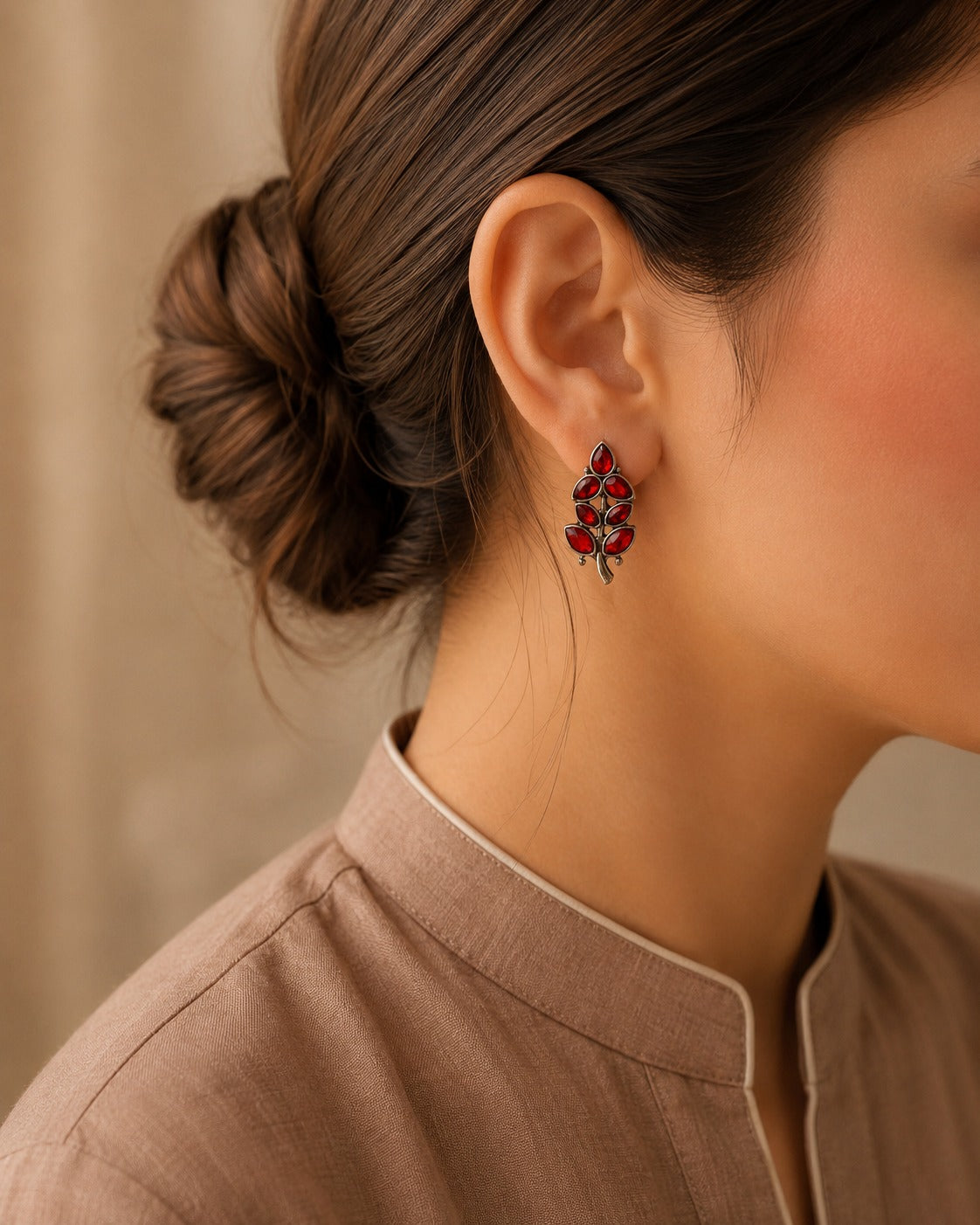 Close-up of a person wearing red floral earrings with a neutral background