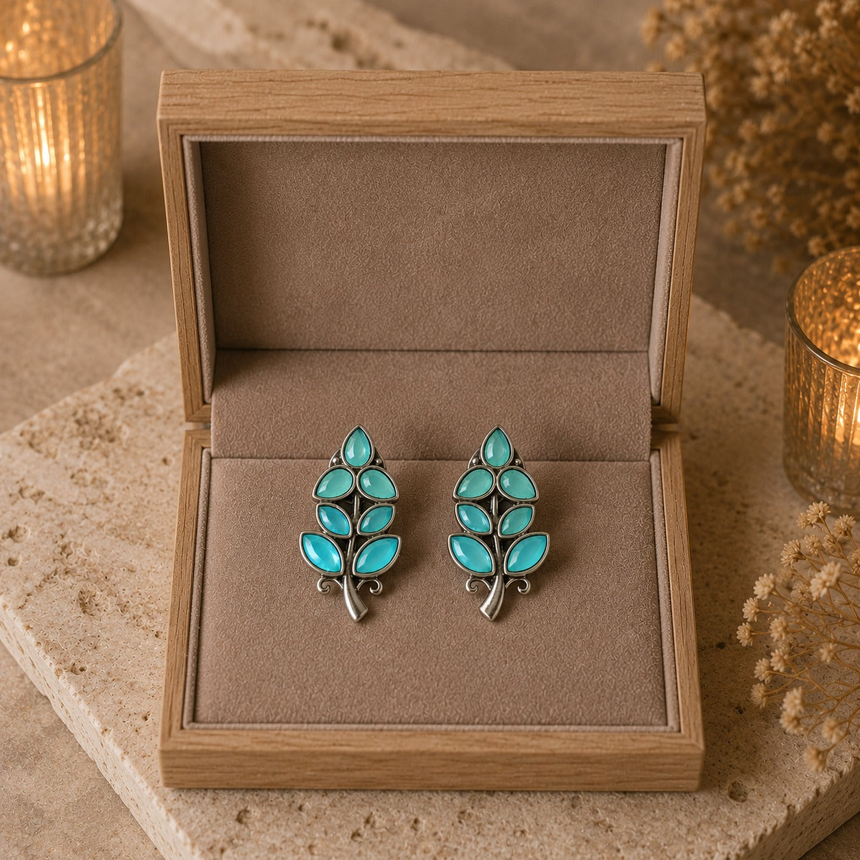 Pair of turquoise leaf-shaped earrings in a wooden jewelry box.
