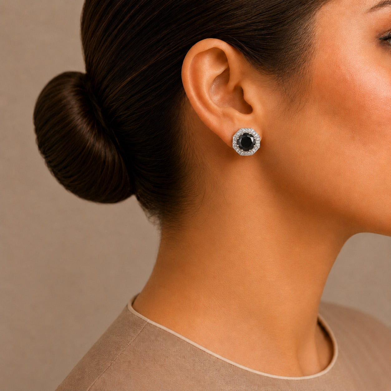 Close-up of a woman wearing a black and silver earring with a neutral background