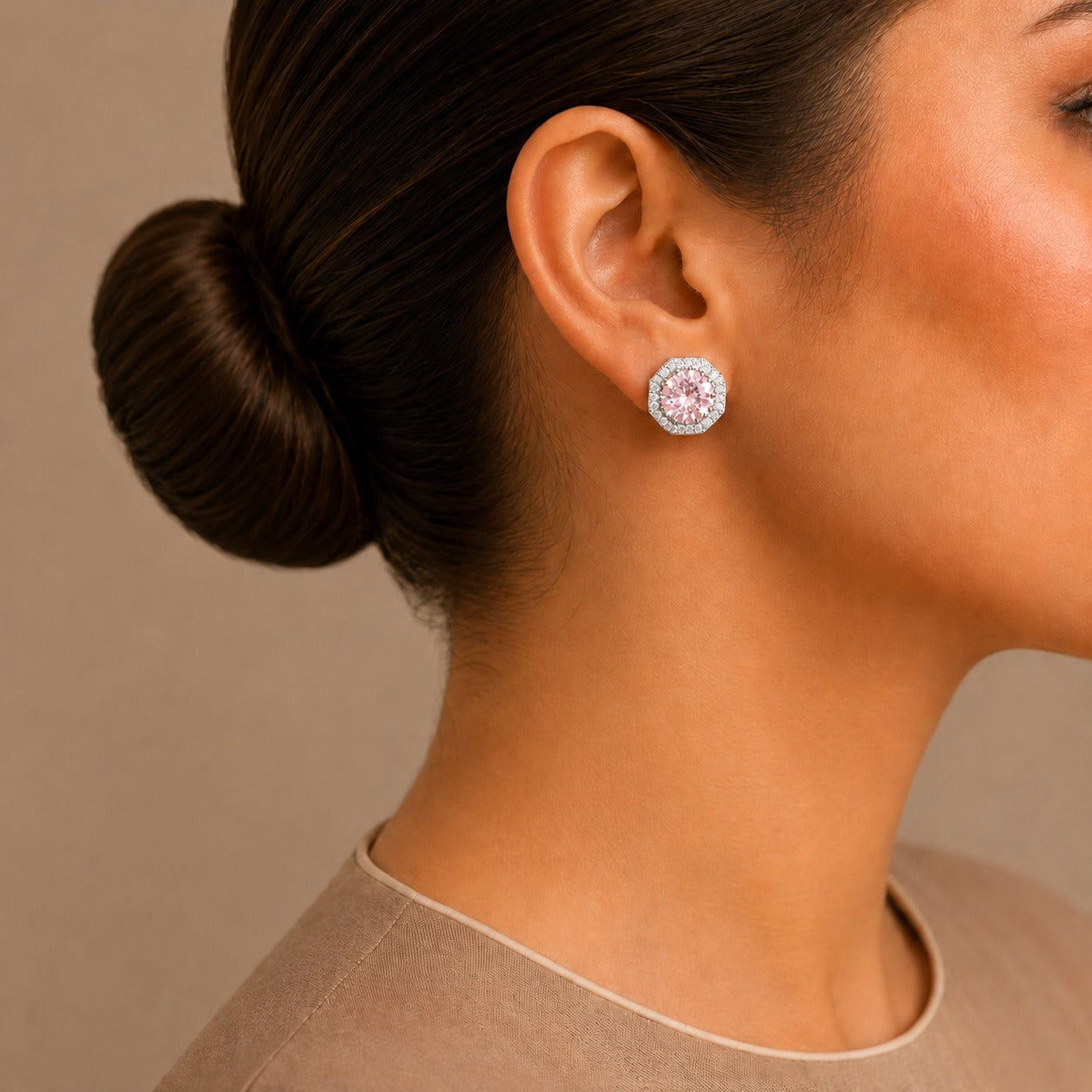 Close-up of a woman wearing a pink central gem earring with a neutral background