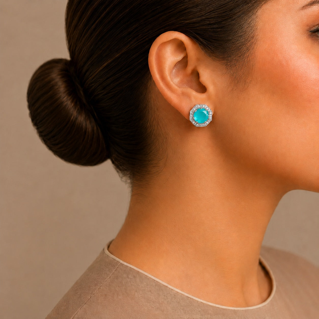 Close-up of a woman wearing a black and silver earring with a neutral background