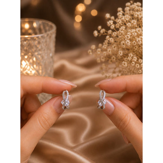 Close-up of premium silver crystal hoop earrings held by hand, featuring marquise-cut stone and pavé detailing.