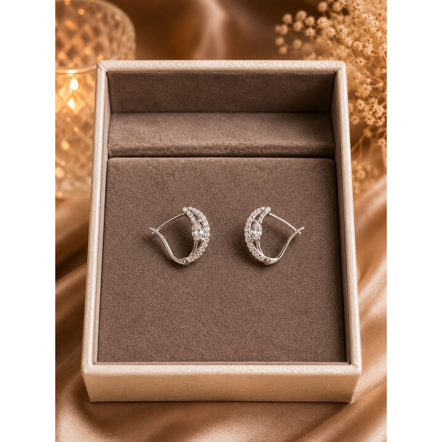 Silver infinity crystal hoop earrings displayed in a luxury velvet jewelry box with sparkling marquise crystal centerpiece