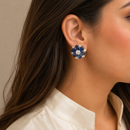 Woman wearing premium royal blue floral crystal stud earrings with pear-cut stones in a luxury side-profile portrait.