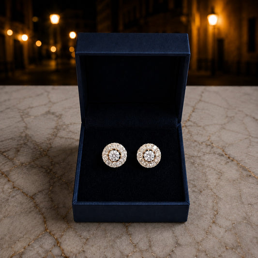 Gold-tone crystal halo stud earrings displayed in a luxury jewellery box with a brilliant round-cut centre crystal and pavé halo.
