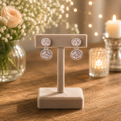 Silver double halo drop earrings with clear/silver crystals displayed on a premium beige velvet jewellery stand.