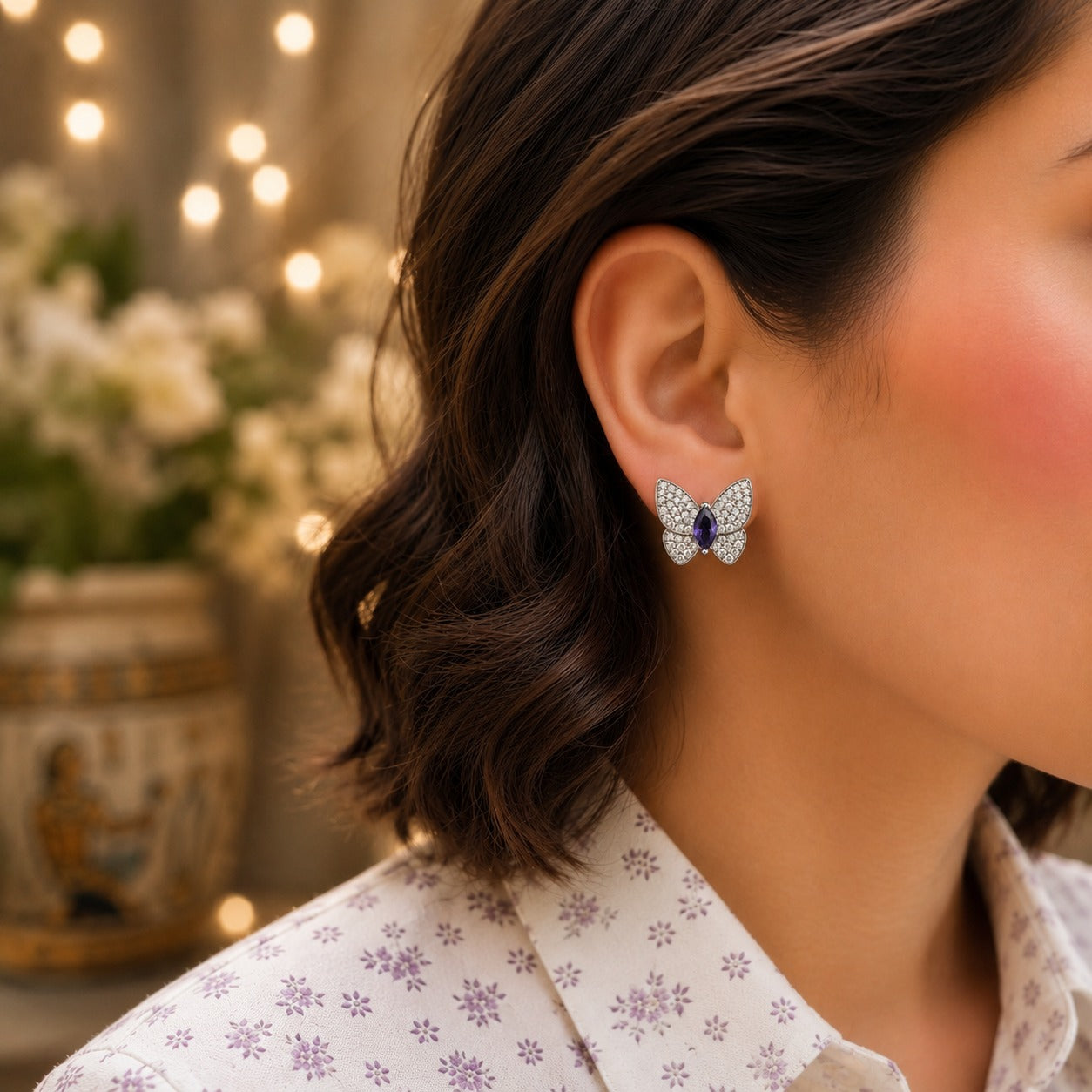 Butterfly stud earrings with a violet marquise-cut gemstone and pavé crystals worn on a model.