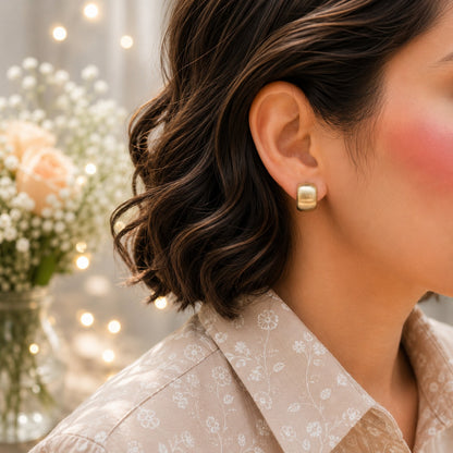 Matte gold mini huggie hoop earrings worn on model with brushed finish and modern minimalist style.