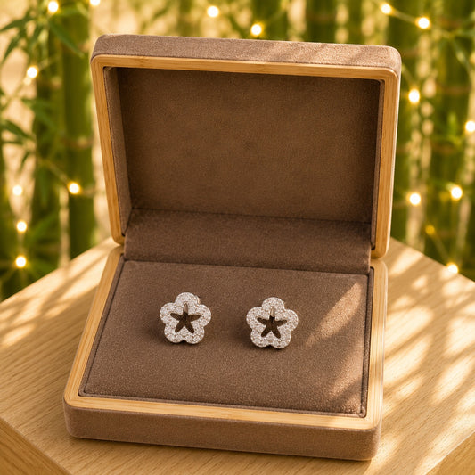 Silver crystal flower stud earrings displayed in a premium mocha velvet jewellery box with a wooden frame on a bamboo tabletop.