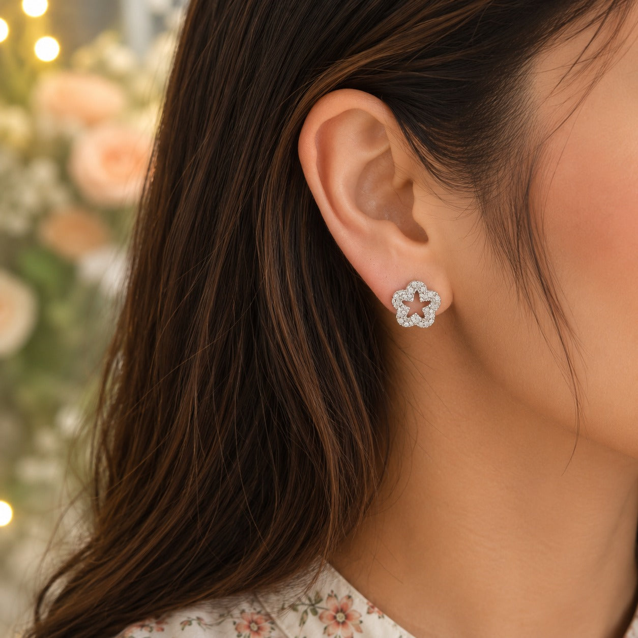 Close-up of a model wearing silver crystal flower stud earrings with sparkling pavé detailing and an open-centre floral design