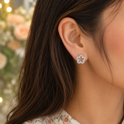 Close-up of a model wearing silver crystal flower stud earrings with sparkling pavé detailing and an open-centre floral design
