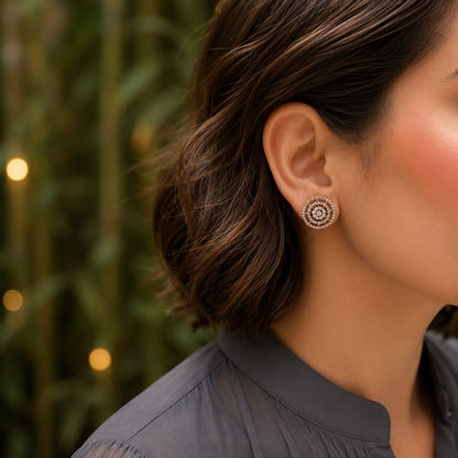 Woman wearing geometric halo crystal stud earrings with a charcoal grey linen shirt in a close-up portrait.