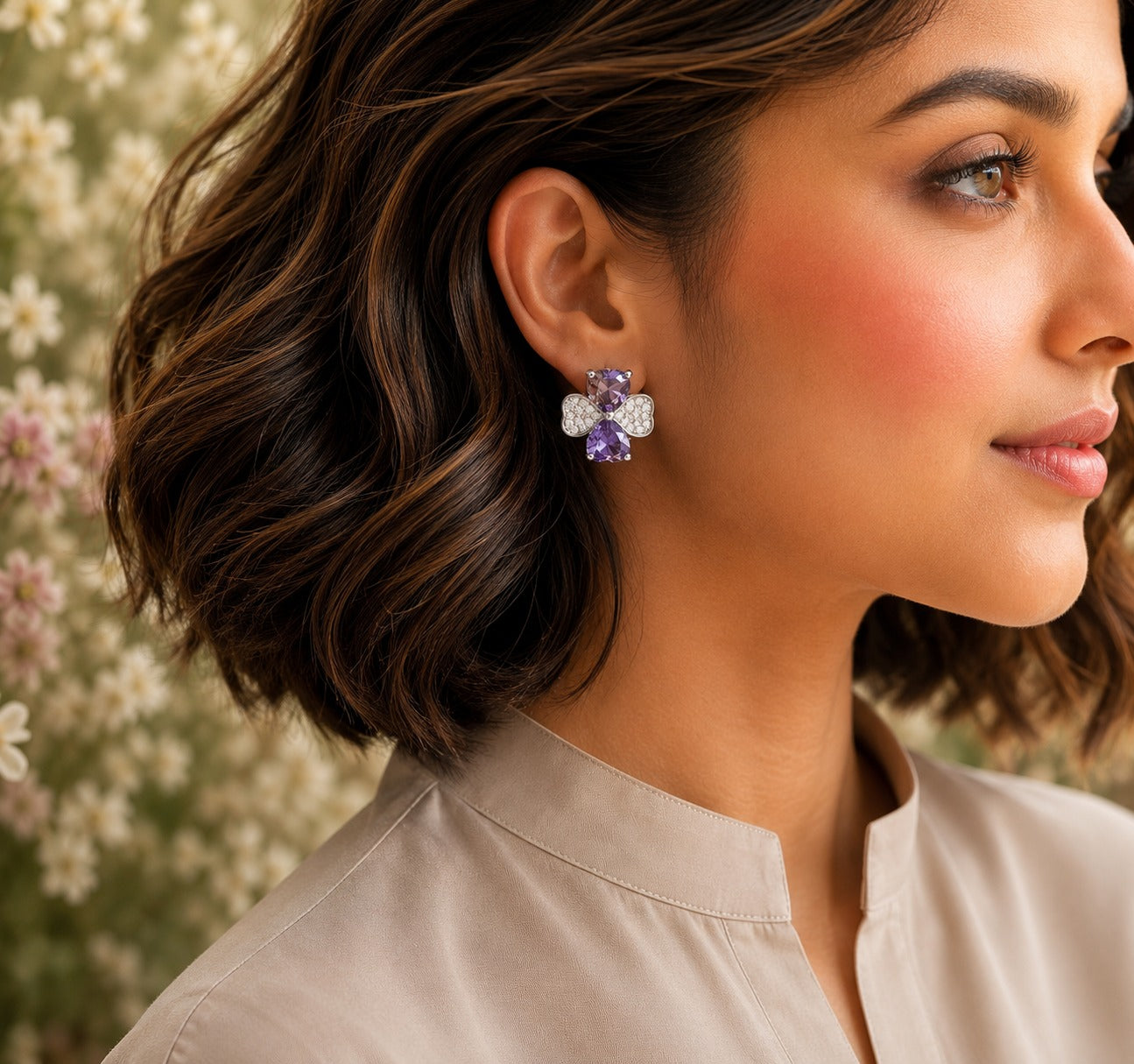 Model wearing silver crystal bow stud earrings with lavender heart-cut crystals.