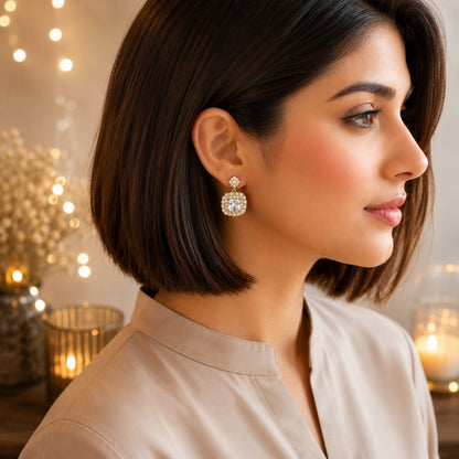 Model wearing gold halo square drop earrings with crystal clear centre crystals and pavé halo detailing.