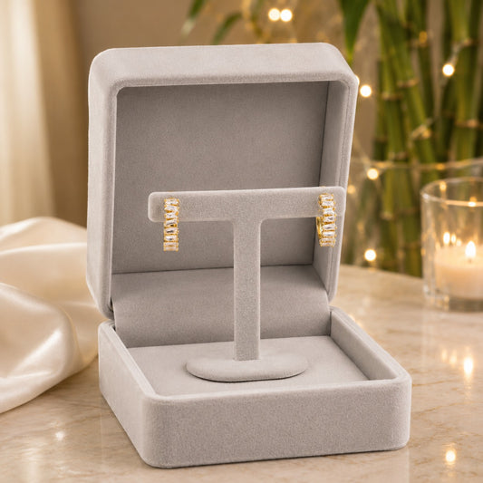 Gold baguette crystal hoop earrings showcased on a luxury velvet jewellery stand with sparkling baguette-cut crystals.