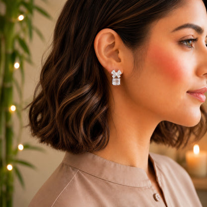 Model wearing floral crystal stud earrings with a clear crystal emerald-cut gemstone drop.