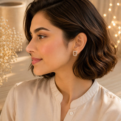 Woman wearing champagne emerald-cut halo stud earrings in silver finish, elegant everyday jewellery close-up