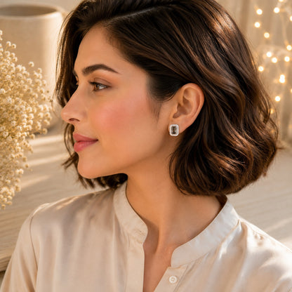 Woman wearing black emerald-cut halo stud earrings in silver finish, luxury statement stud earrings