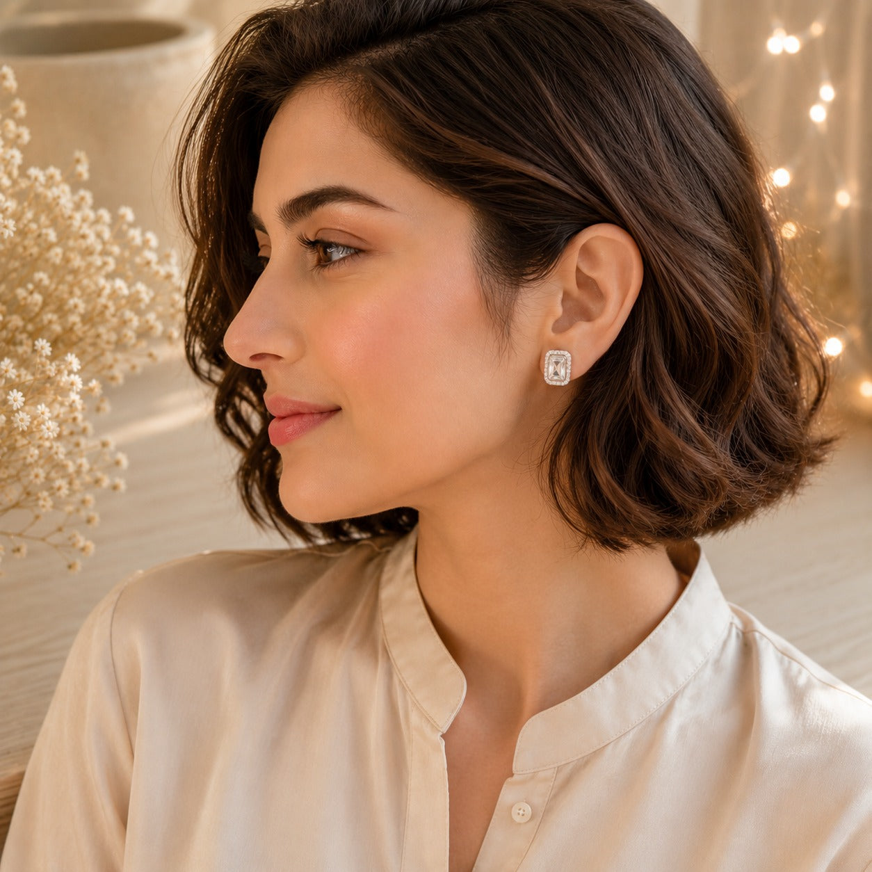 Woman wearing crystal white emerald-cut halo stud earrings in silver finish, luxury everyday jewellery close-up