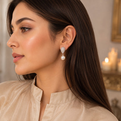 Woman wearing elegant silver pavé crystal teardrop earrings with a classic pearl drop in a luxury side-profile portrait.