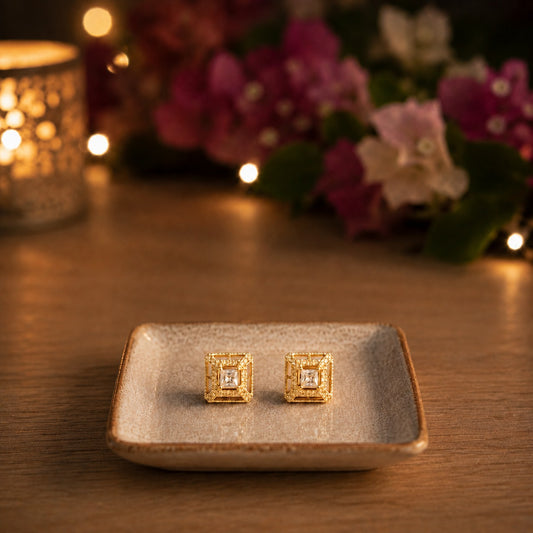Square gold halo crystal stud earrings displayed on a ceramic tray