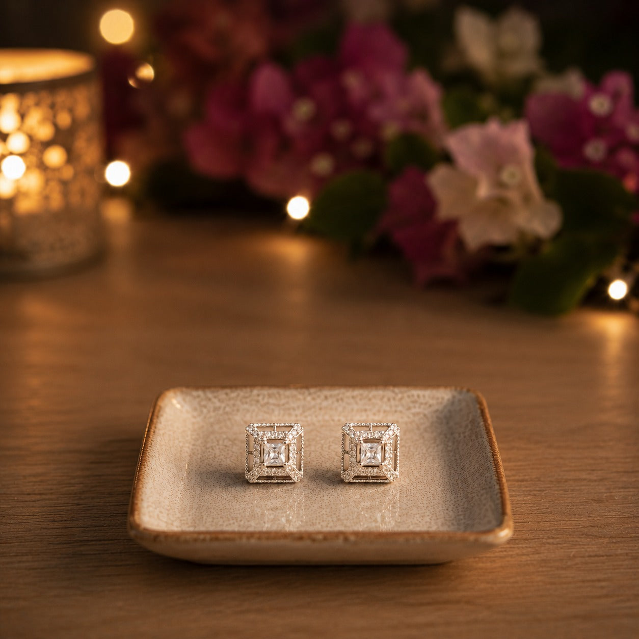 Square silver halo crystal stud earrings displayed on a ceramic tray