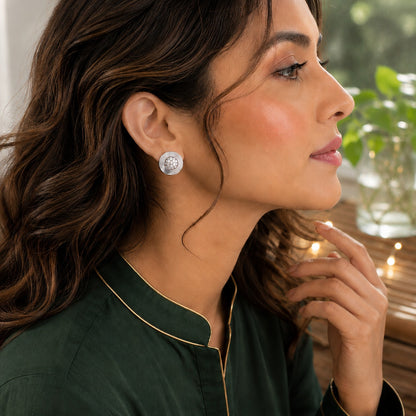 Model wearing silver round crystal disc stud earrings in a polished metal finish with a side-profile portrait in natural daylight