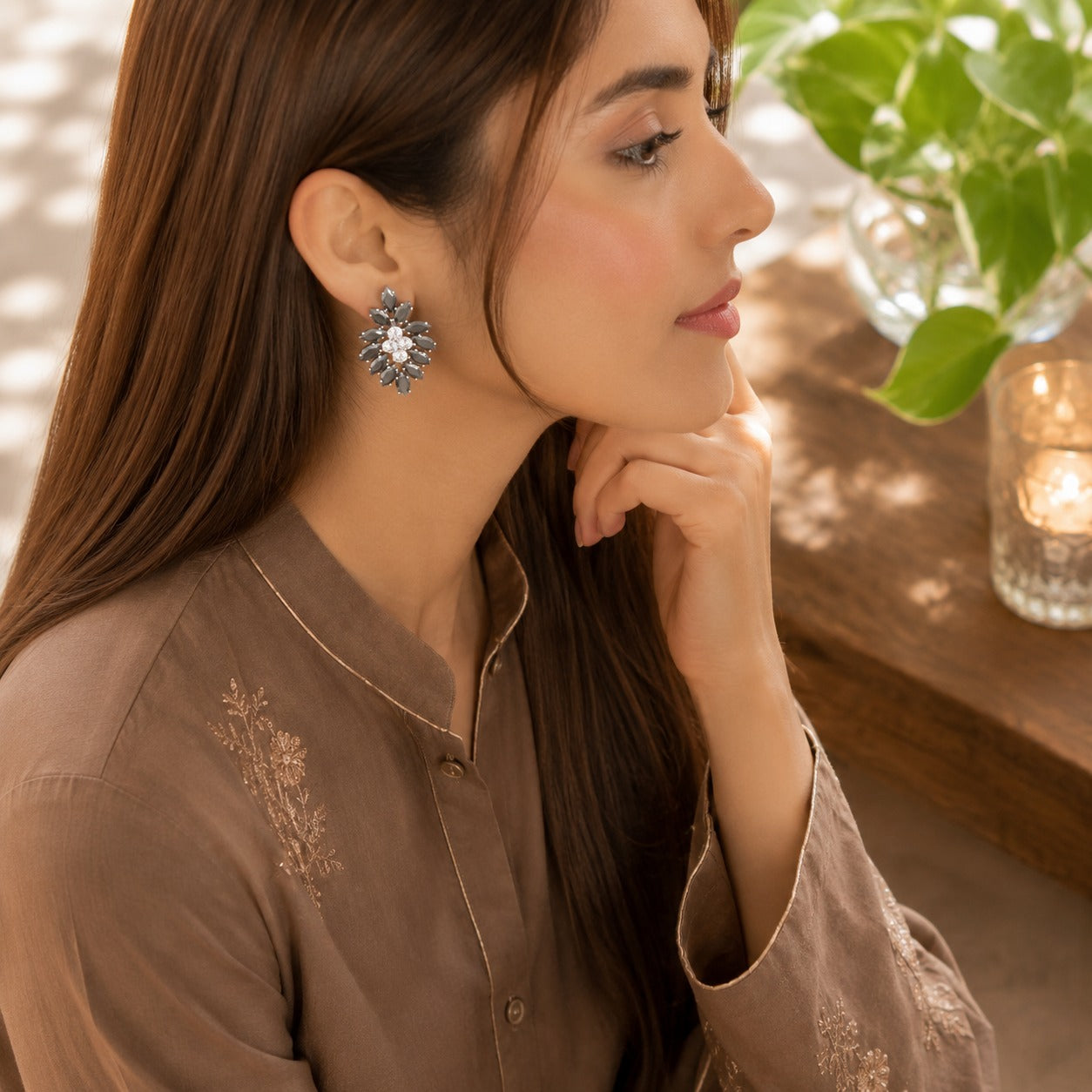 Model wearing black crystal floral statement earrings with a sparkling clear crystal center in a side-profile lifestyle portrait.