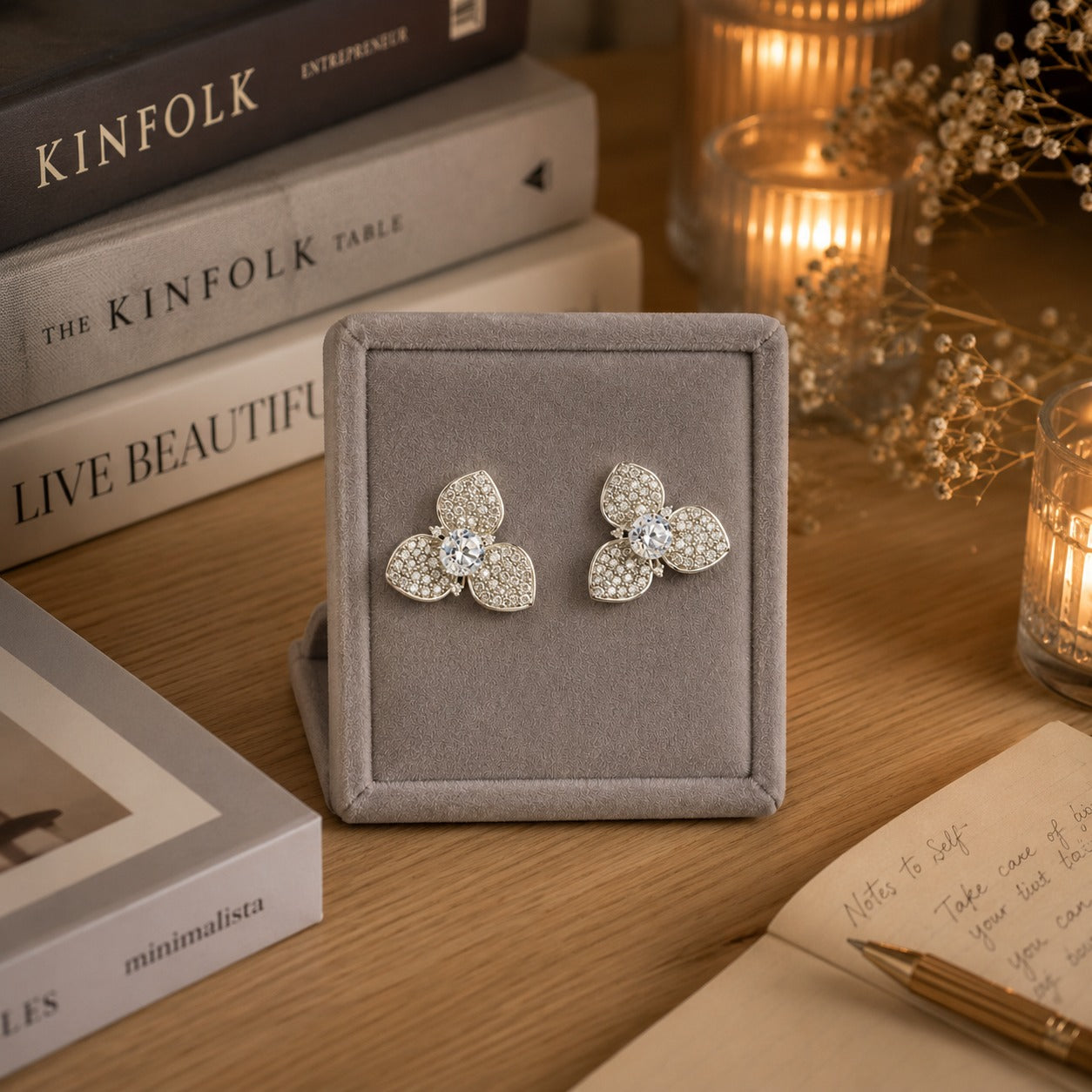 Pair of silver crystal floral stud earrings with pavé crystal petals and a brilliant center stone displayed on a premium grey velvet jewelry stand.