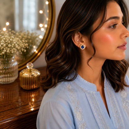 Woman wearing blue round halo gemstone stud earrings in a side-profile portrait with a premium dressing table background.