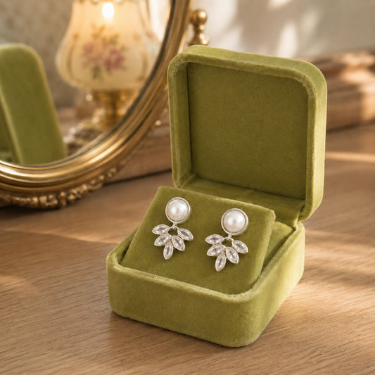 Pearl and marquise  silver crystal drop earrings displayed in a premium olive green velvet jewellery box on a wooden dressing table.