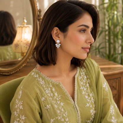 Woman wearing pearl and marquise  silver crystal drop earrings with a light olive embroidered outfit in a bright luxury indoor setting.