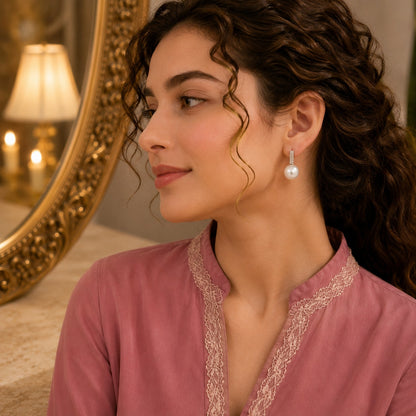Model wearing silver crystal and pearl leverback earrings with a soft pink embroidered outfit in a luxury indoor setting