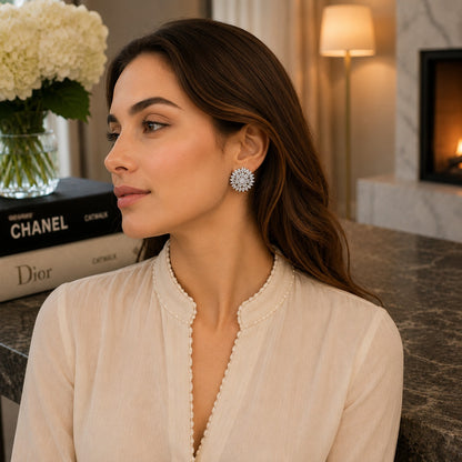 Model wearing silver floral crystal leverback earrings with an ivory outfit in a luxury indoor setting.