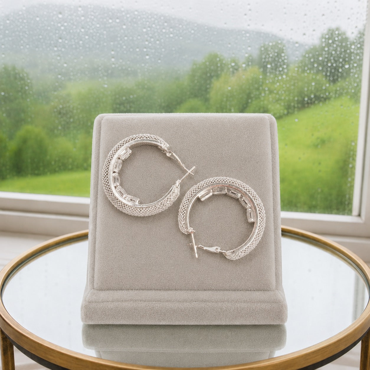 Rear view of silver textured hoop earrings showing the secure hinged snap-lock clasp and textured crystal finish on a luxury velvet display stand.