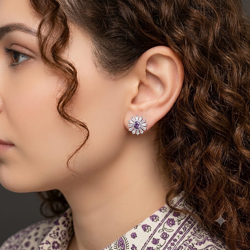Close-up side profile of a model wearing silver floral crystal stud earrings featuring a sparkling purple center stone.